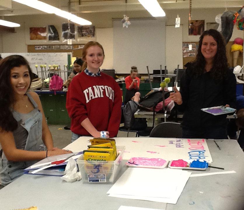 Gabrielle McCracken and two other club members decorating posters for the fundraiser.