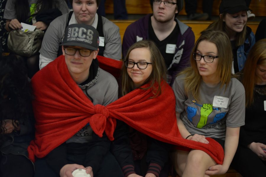 Brandon Nivens and Natalie Geillenfeldt share blanket next to Daelynn Reider while watching presentations and protest.