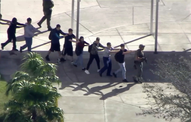 Students from Mary Stoneman Douglas High School in Parkland, Fla., evacuate the school following a shooting, Wednesday, Feb. 14, 2018.