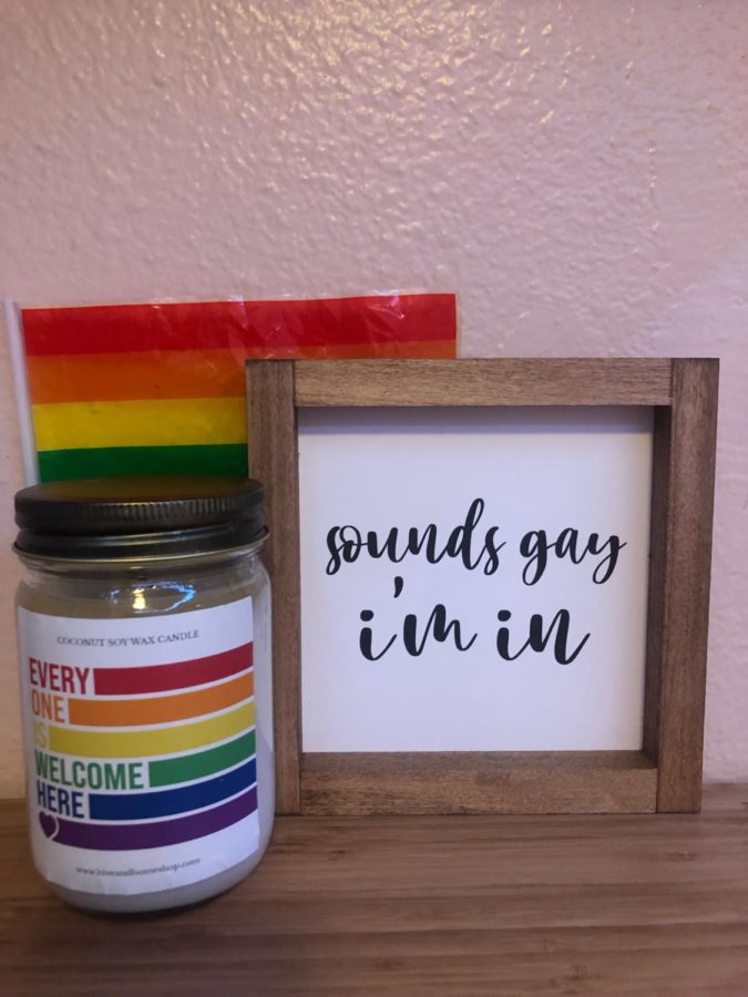 A celebratory Pride candle, sign, and flag. 