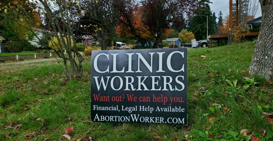 A black sign with the words CLINIC WORKERS; Want out? We can help you. Financial, Legal Help Available; AbortionWorker.Com