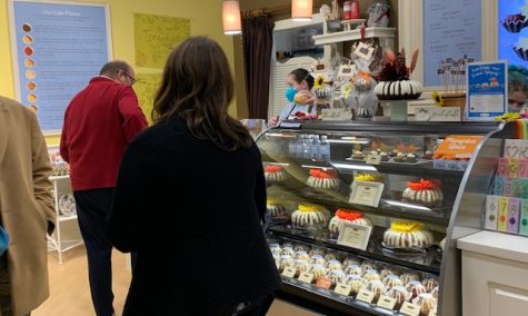 People at the bakery ordering cakes. Everyone is in a good mood. 