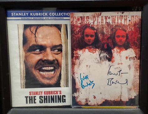 A poster of and signed by the infamous twins from The Shining, stored next to a DVD copy of the movie.