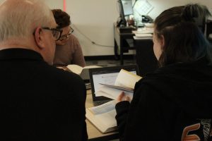 Lance Coyer sits down with a student to assist them with an assignment in his financial math class.