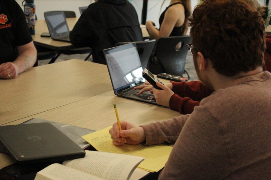 A group of students work on their financial math assignments. The class incorporates a mix of practice work, projects, and tests. 