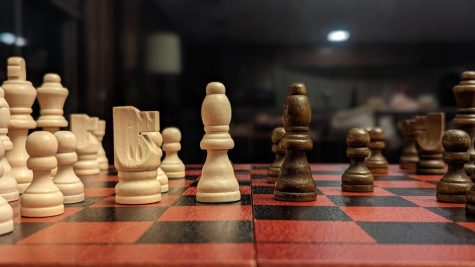 A physical chess game in progress on a wooden board.