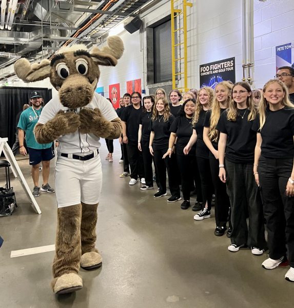 The Mariners Moose, who is standing beside the Central Kitsap Choir.