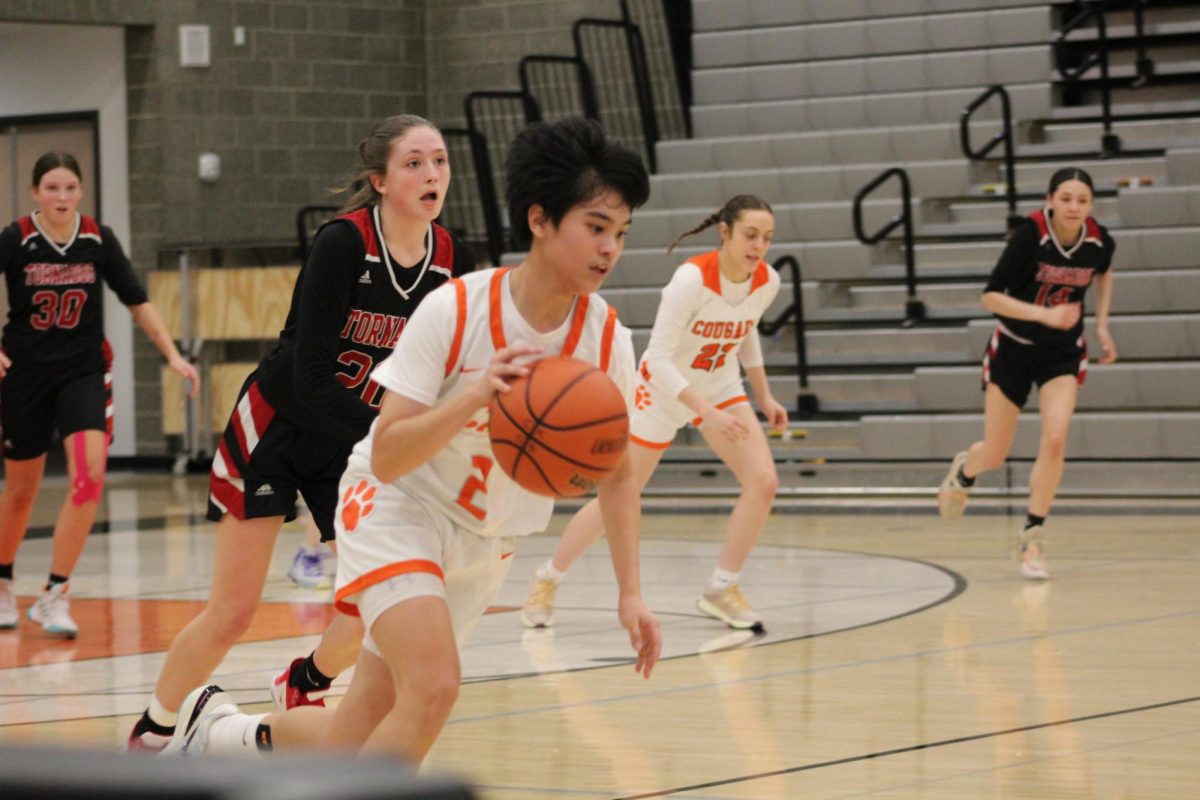 Jillianne Farrales, player #21 on the team (jersey #2) makes a charge towards the other end of the court with the opposing following closely behind. 