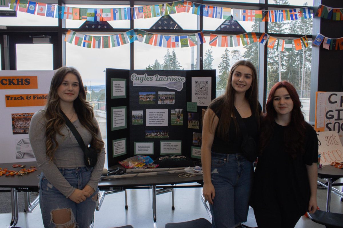 Olivia Keough (left), Trinity Ranes (center), and Ellie Shoemaker (right) posing for a photo in front of their team trifold.