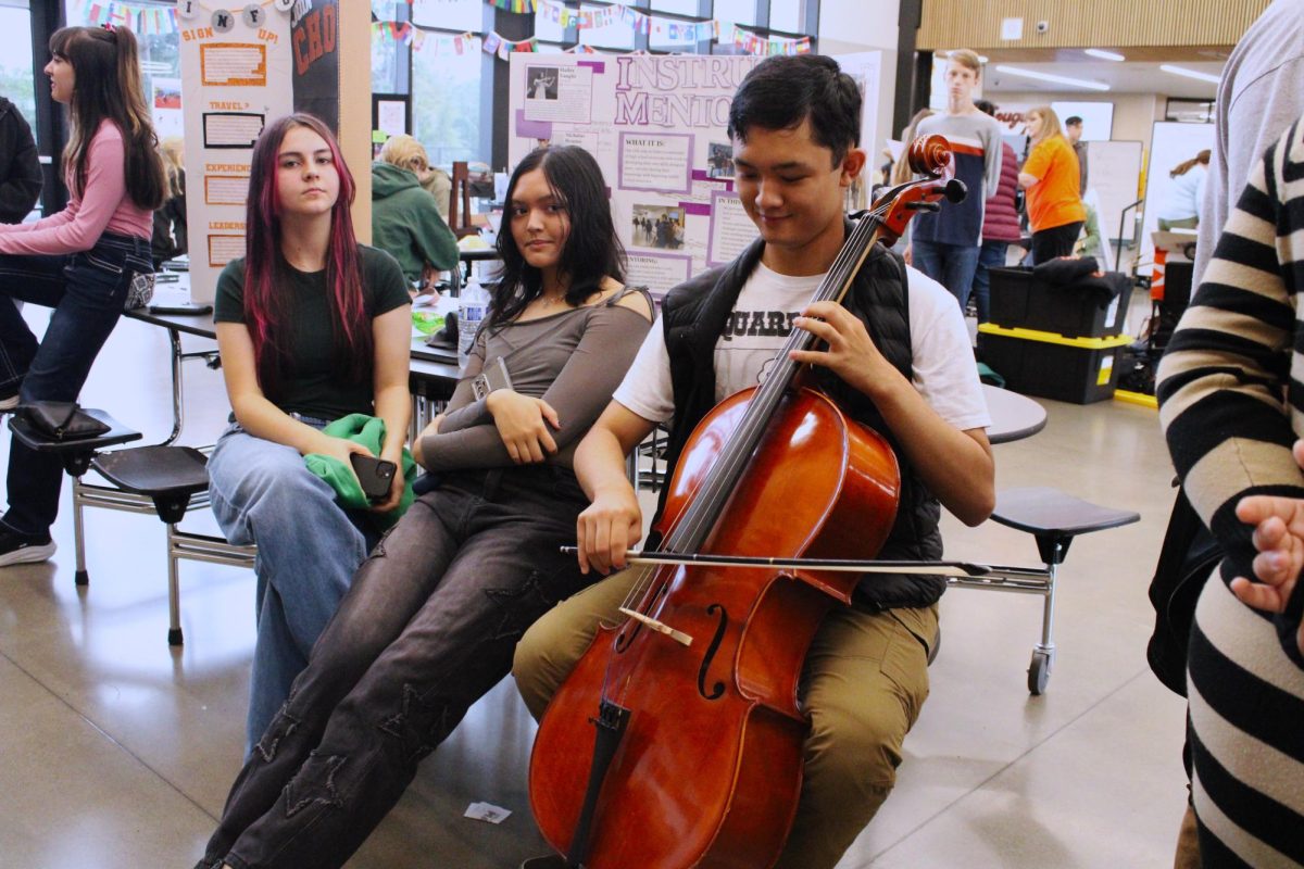 Jadon Alina playing the cello at his booth during Maze Days