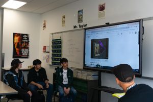 During one of The Underground Music Club's after school meetings, members and adviser Blair Taylor gather around the smartboard to listen to a song together.