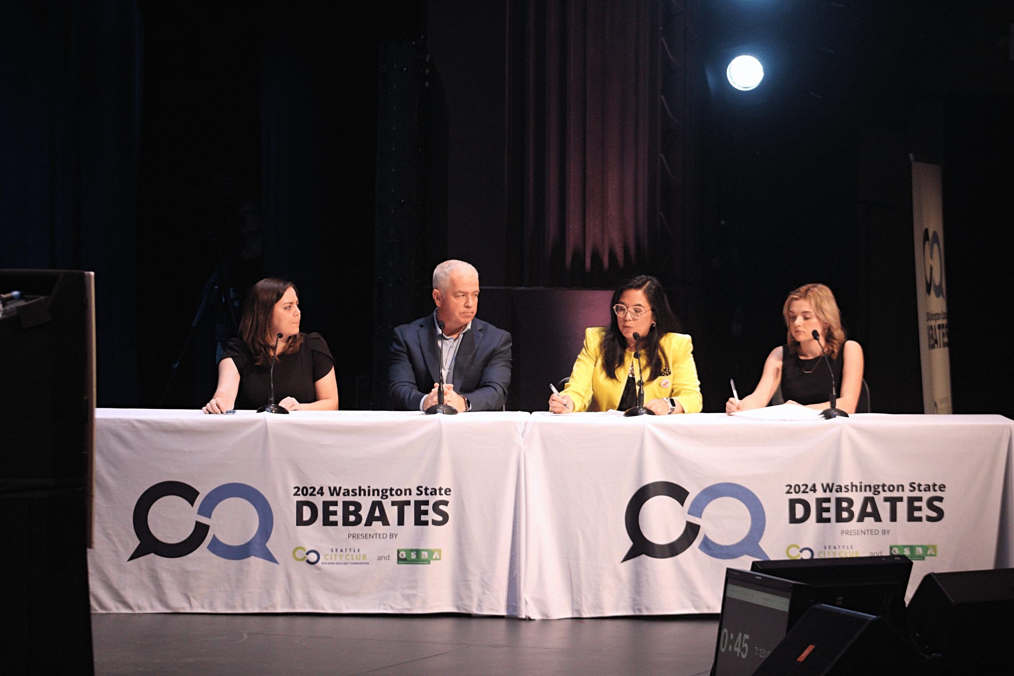 Moderators Sami West (left), John Hopperstad (left center), Venice Buhain (right center), and Kellyanna Brooking (right) asking the candidates questions during the debate. 