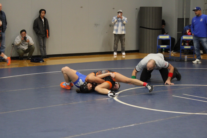 Deijah Diego on the mat as she pins her opponent during her match.