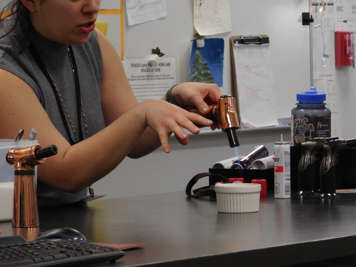 Alicia Flint demonstrates how to caramelize sugar on top of crème brûlée using a torch.
