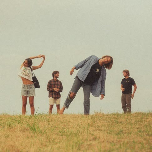 Band members Brook Tuozzo, Patrick Helrigel, Nick Mateyunas, and Austin Jones (left to right) mingling and playing with the camera on a hilltop. 