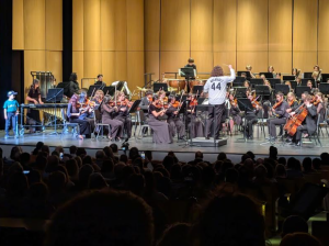 Michael Woods (center) conducts the Kitsap Philharmonic orchestra playing "Seventh Inning Stretches" while his son Henry Woods stands prepared to mime hitting a home run (left). Provided by Deanna Gemmer