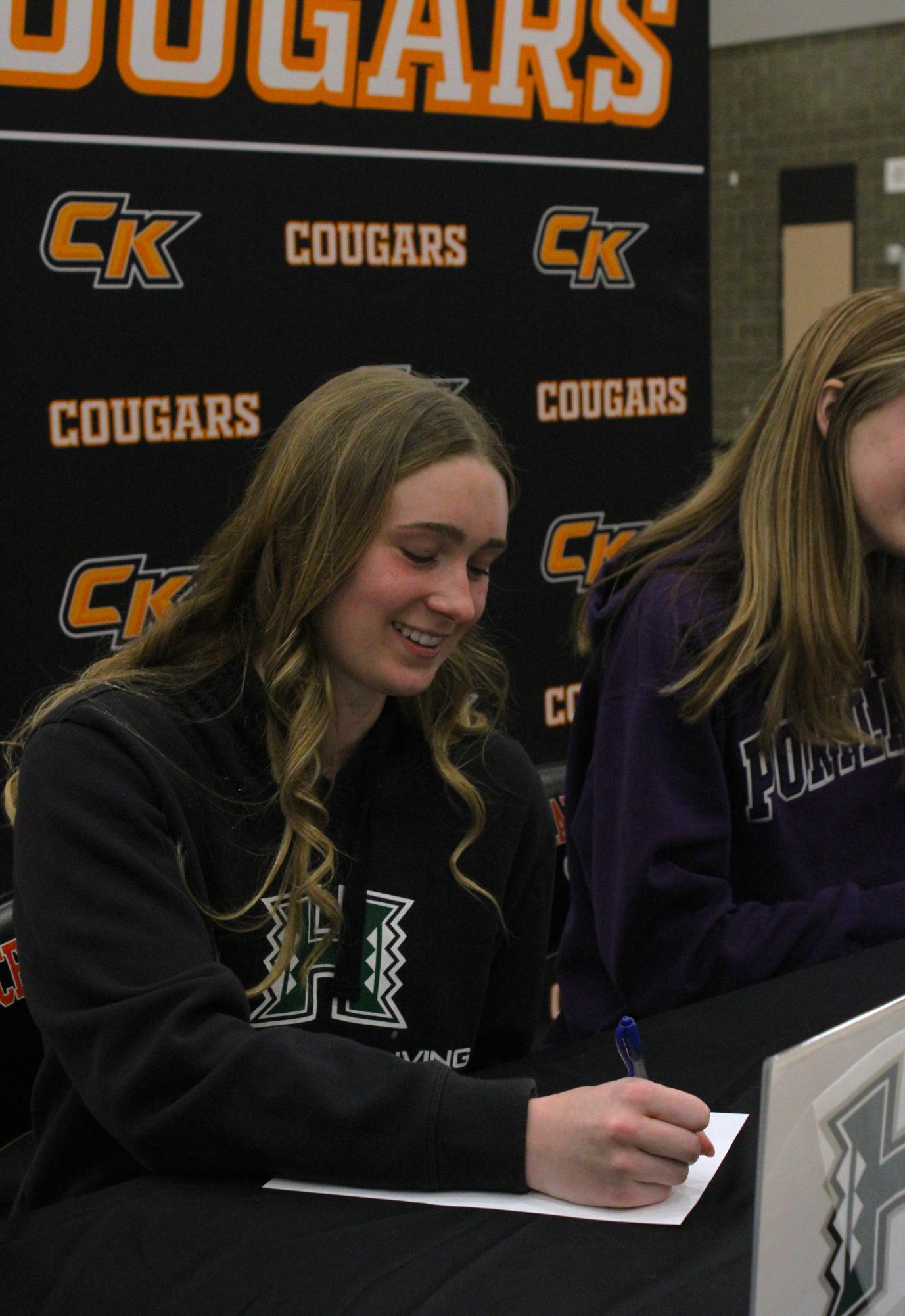 Swim athlete Aziza Meyer signs the University of Hawaii's recruitment paper. 