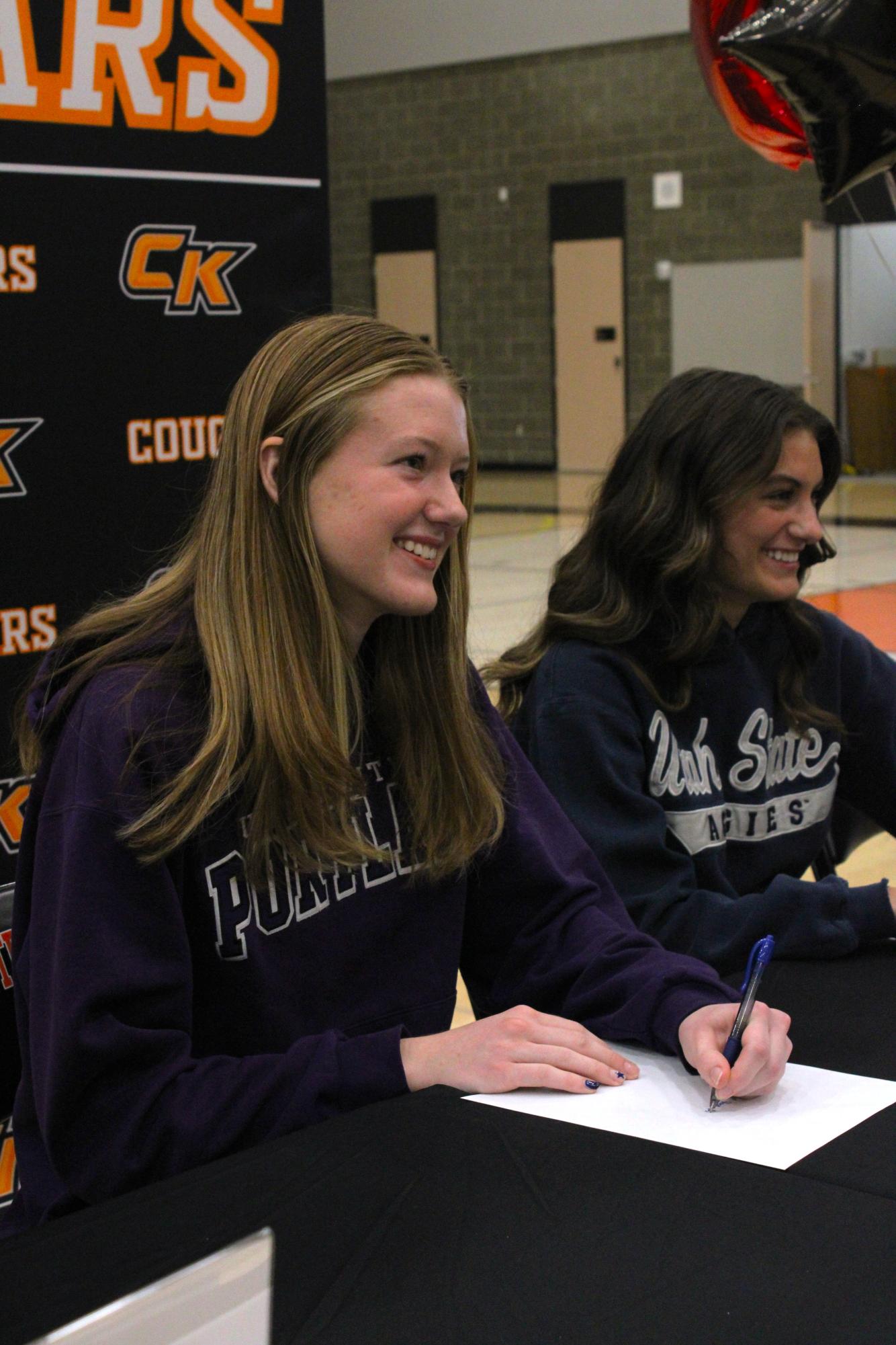 Track and cross-country athlete Claire Herring looks up to smile after signing the University of Portland's recruitment paper. 