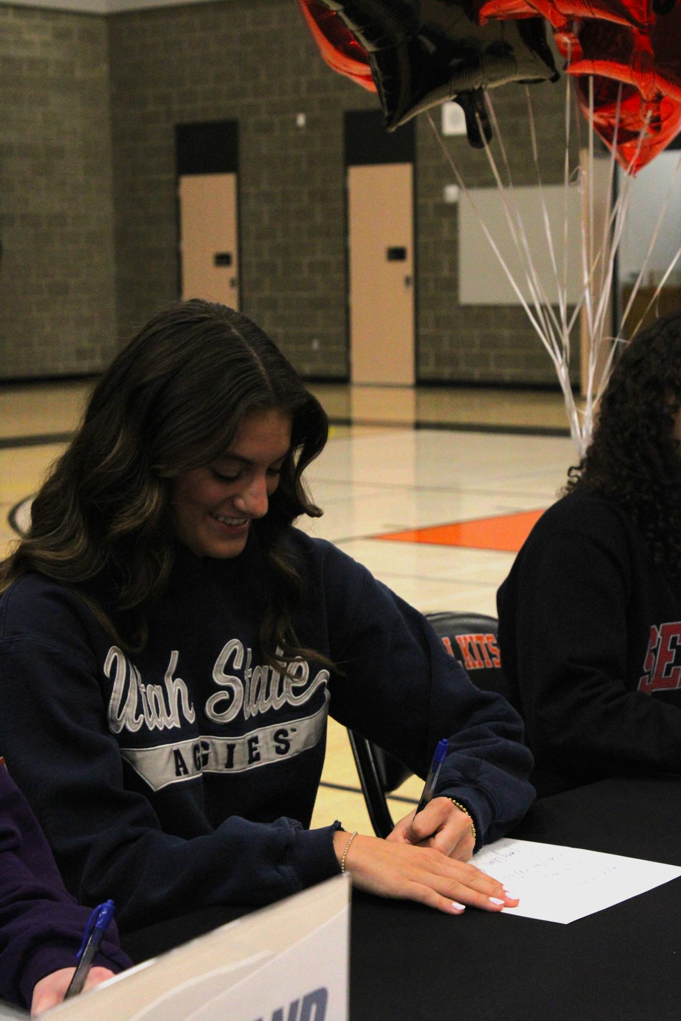 Track and cross-country athlete Taylor Palmer signs Utah State Universities' recruitment paper. 