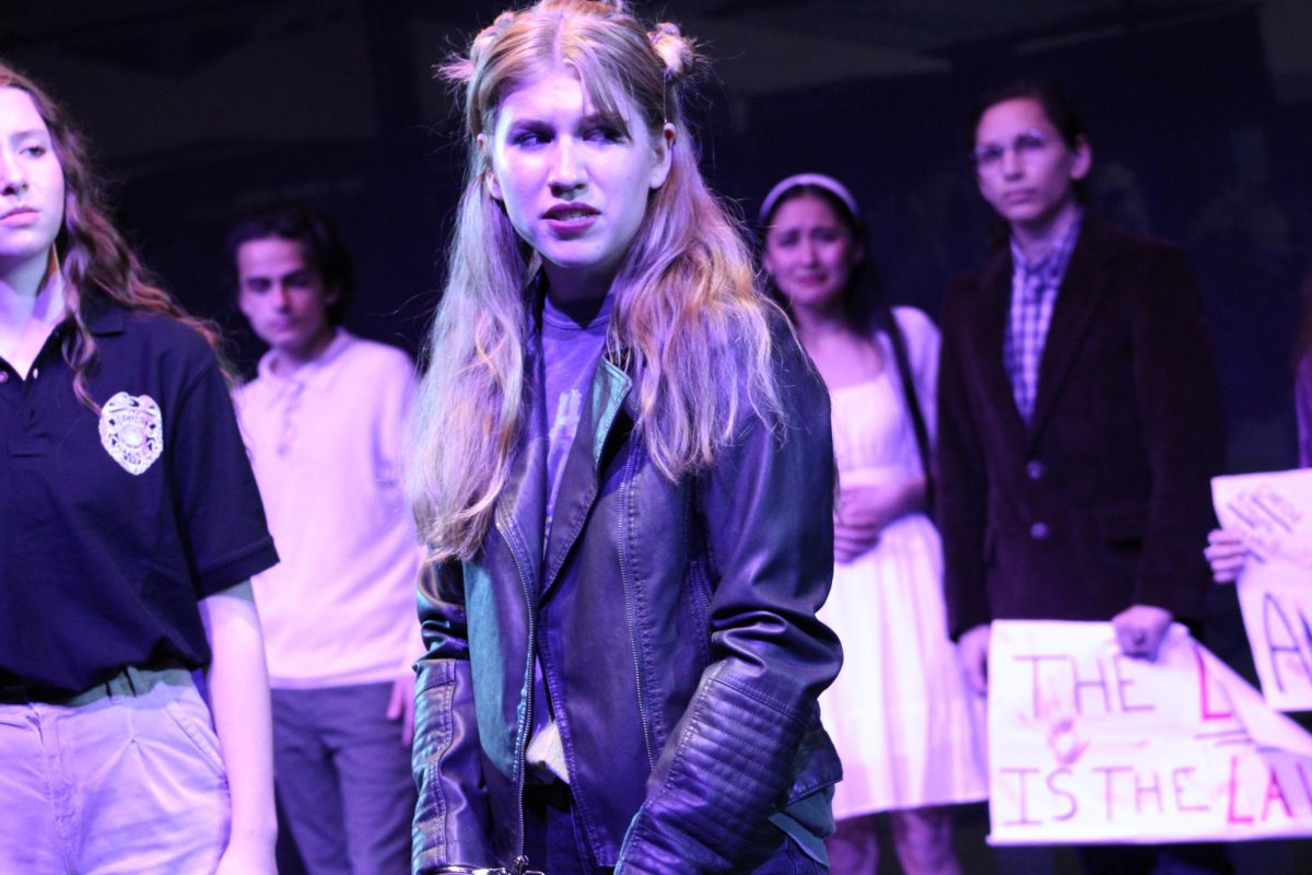 Hannah Baugh as Antigone glances around worriedly at the protesters.