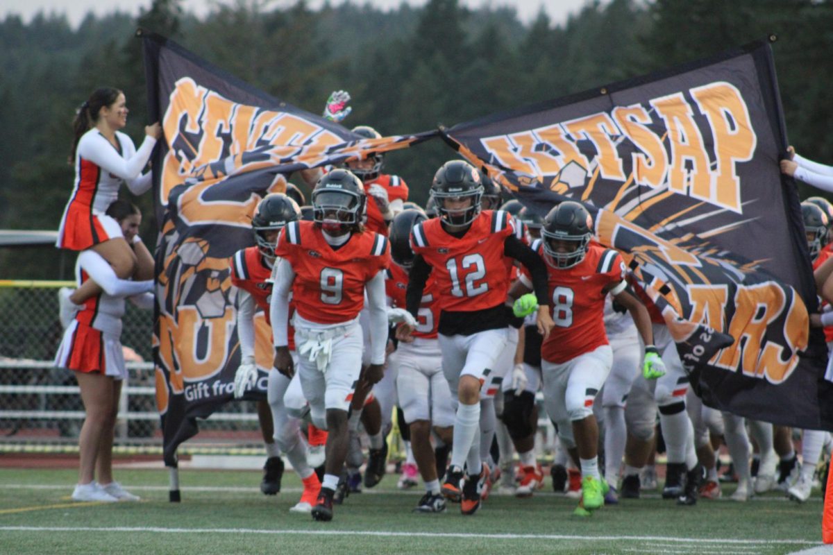 Central Kitsap Cougars tearing through the sign as their entrance to the football game.