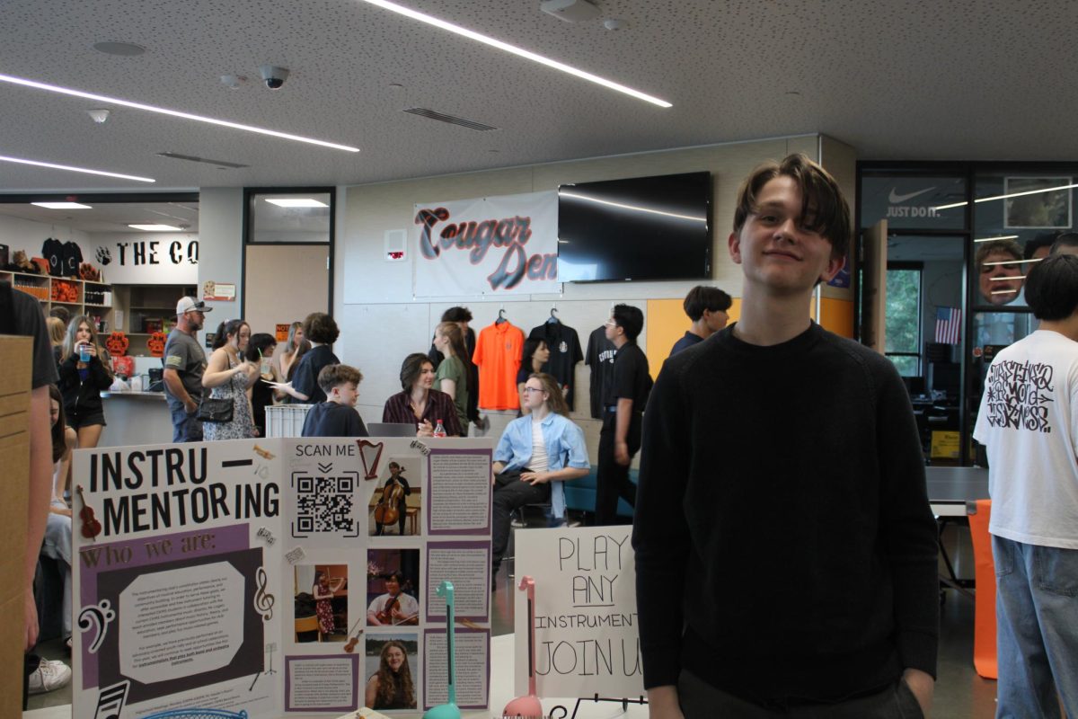 Logan Keeley stands by the Instru-Mentoring Club trifold.