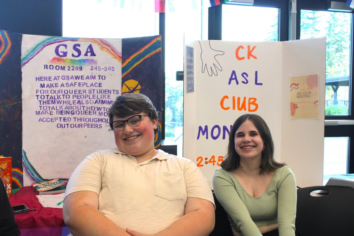 Samuel Campagna (left) and Delaney Kish (right) smile in front of the American Sign Language Club booth.
