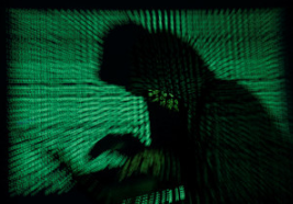 A hooded man holds a laptop computer as cyber code is projected on him in this illustration picture taken on May 13, 2017. (Kacper Pempel)