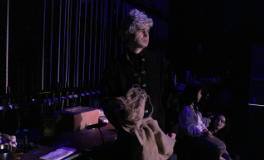 Miles Borer waiting on stage right for his moment to come on stage, holding a burlap sack
