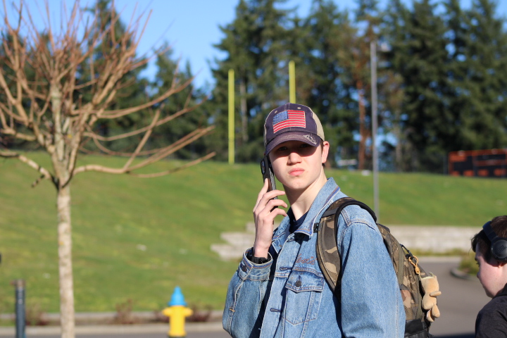 A student makes a call while waiting for the bus.