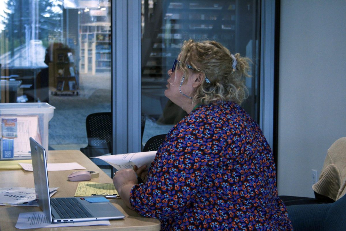 Vasilika Culako greets a taxpayer while discussing necessary paperwork during the tax aide event.