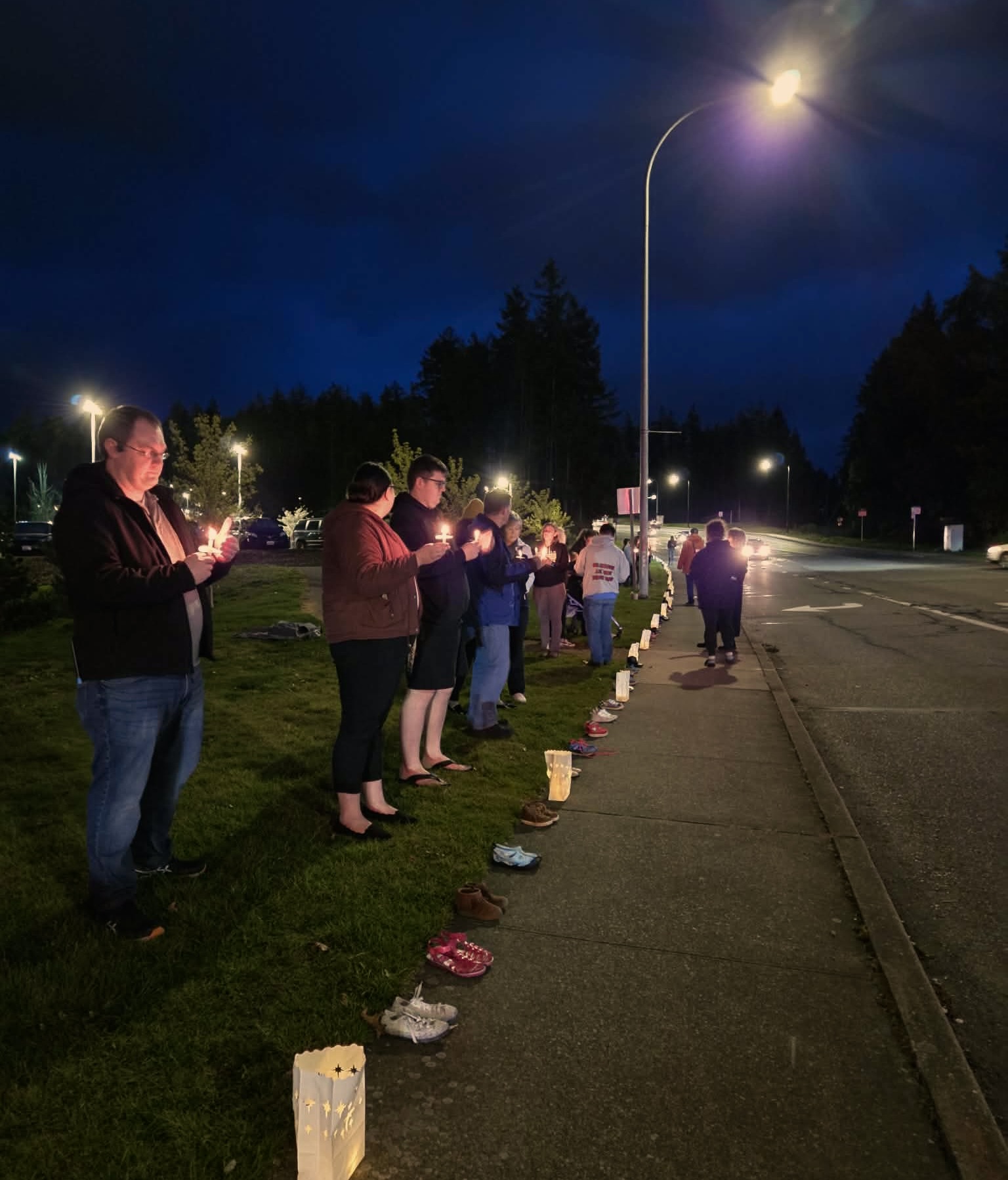 A community of people against St. Michael Medical Center closing down the Pediatric Rehabilitation Center at the vigil held on April 2, stand behind a line of 250 children's shoes representing each child's endeavor. (Provided by Tommy Debord)