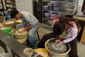 Joseph Ortega and Norah Gutierrez throw bowls on the potters' wheel.