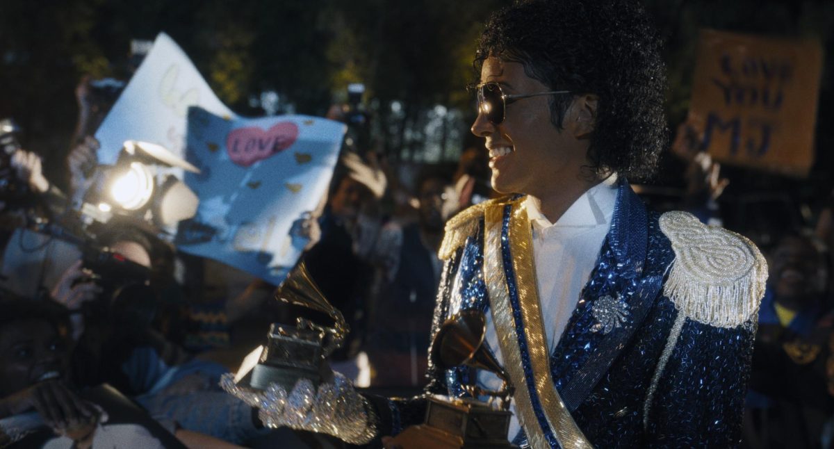 Pop star Micheal Jackson (Jafaar Jackson) smiles while holding a grammy award as he looks on at fans holding posters. Provided by Lionsgate studios.
